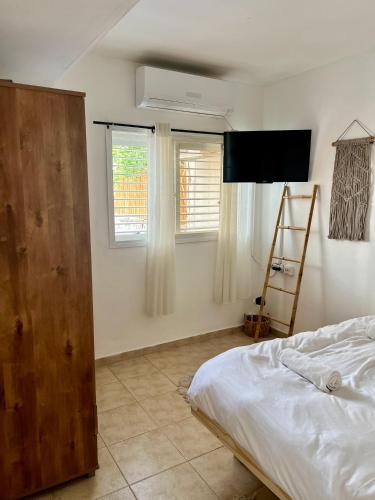 a bedroom with a bed and a tv and two windows at Melambai in Eilat
