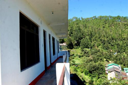 einen Balkon eines Hauses mit Blick auf die Bäume in der Unterkunft Snow View Guest House Kausani & homestay in Kausani