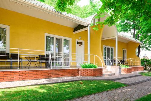 a yellow house with a porch and a patio at Sovinyon Resort in Odesa