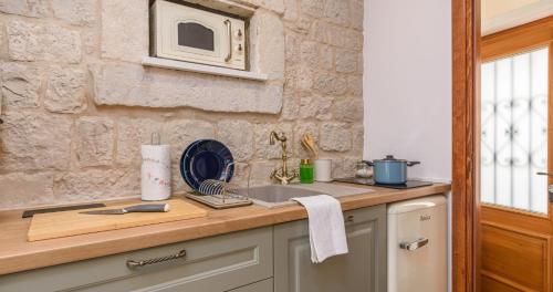 a kitchen with a counter with a microwave on the wall at Oleander Trogir Suites in Trogir