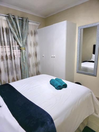 a bedroom with a white bed with a blue towel on it at Peshline Guest House Unit 2 in Ermelo