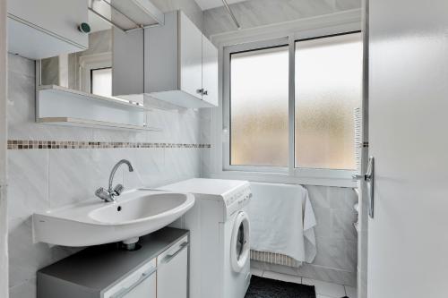La salle de bains blanche est pourvue d'un lavabo et d'un lave-linge. dans l'établissement T2 Cosy Jardin Port & Plage tout à pied, au Pouliguen
