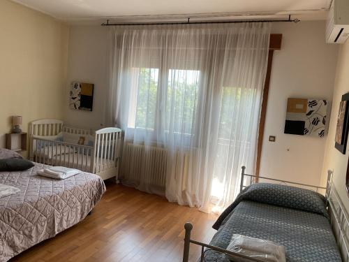 a bedroom with two beds and a large window at Villa tre Cai, vicina al mare e a Jesolo in Eraclea