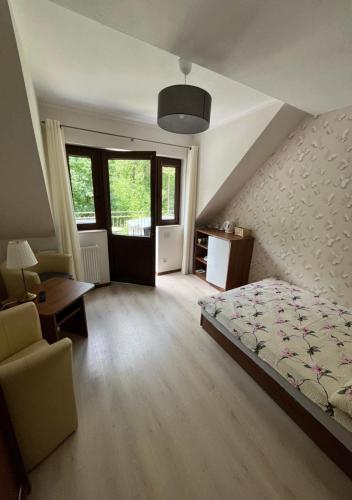 a bedroom with a bed and a desk and windows at Pokoje & Domki GABI in Pobierowo