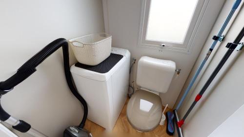 Elle comprend une petite salle de bains pourvue de toilettes et d'une fenêtre. dans l'établissement Mobil Home avec Clim La Plage, à La Parée Preneau