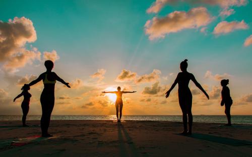a group of people standing on the beach watching the sunset at Ostrov Palm in Ukulhas