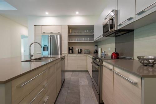 a large kitchen with stainless steel appliances and white cabinets at Beachfront Jungle Luxury! 3BD Penthouse Uvita in Uvita