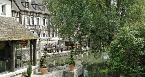 Un grupo de personas sentadas en bancos junto a un río. en Maison Saint Pierre, en Chartres