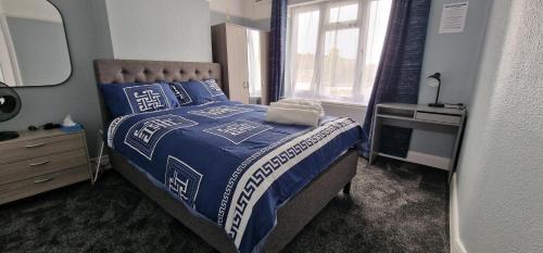 a bedroom with a bed with a blue comforter and a window at Rowan Crescent's Luxury Stay-In 3 in Streatham Vale