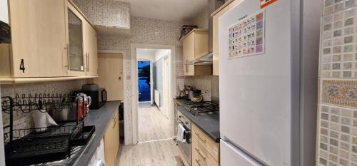 a kitchen with a white refrigerator and a stove at Rowan Crescent's Luxury Stay-In 3 in Streatham Vale