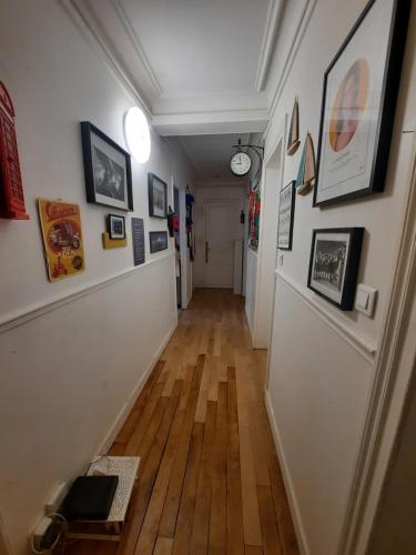 un long couloir avec une horloge sur le mur dans l'établissement Appartement familial dans le 16é, à Paris