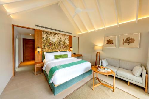 a bedroom with a bed and a couch at RAAYA By Atmosphere - Premium All Inclusive with Free Transfers in Raa Atoll