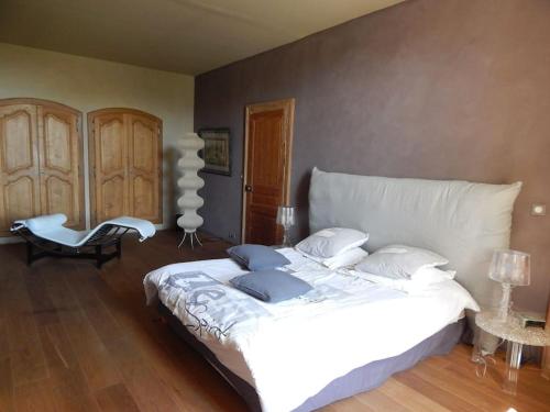 une chambre avec un grand lit blanc et une chaise dans l'établissement Spacieuse maison de village avec piscine, à Saint-Mathieu-de-Tréviers