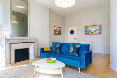 a living room with a blue couch and a table at Appartement T3 de Prestige proche du Jardin Public de Bordeaux in Bordeaux