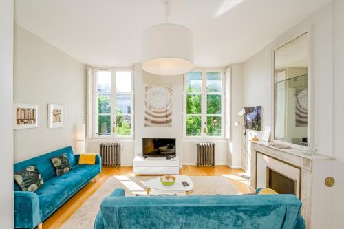 a living room with a blue couch and a fireplace at Appartement T3 de Prestige proche du Jardin Public de Bordeaux in Bordeaux