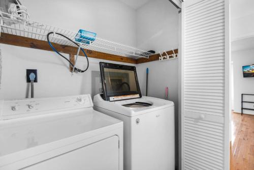 a white laundry room with a tv on top of a washing machine at Sandcastle 20 -Navarre a Dull Moment in Navarre