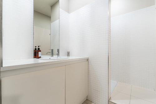 a white bathroom with a sink and a mirror at Appartement T3 de Prestige proche du Jardin Public de Bordeaux in Bordeaux