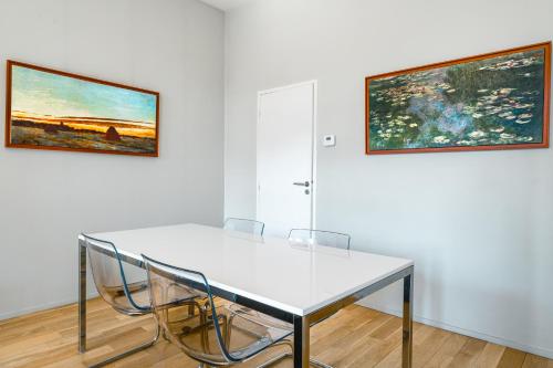 a white table and chairs in a room with two paintings at Appartement T3 de Prestige proche du Jardin Public de Bordeaux in Bordeaux