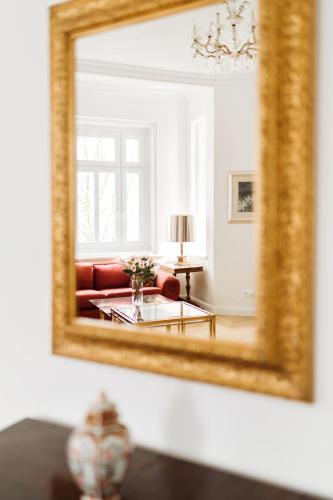 a living room with a red couch and a mirror at Golf Apartment Villa Elisabeth in Mariánské Lázně