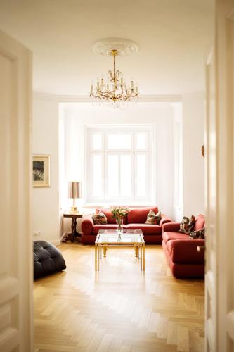 a living room with red couches and a chandelier at Golf Apartment Villa Elisabeth in Mariánské Lázně