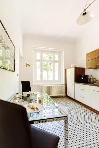 a living room with a glass table and a kitchen at Golf Apartment Villa Elisabeth in Mariánské Lázně