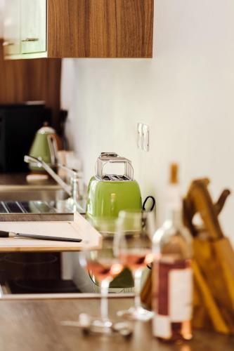a kitchen counter with a green toaster and a glass of wine at Golf Apartment Villa Elisabeth in Mariánské Lázně