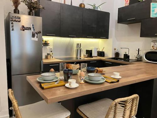 Il comprend une cuisine équipée d'une table avec de la vaisselle et d'un réfrigérateur. dans l'établissement Un petit cocon en plein cœur du 11eme, à Paris