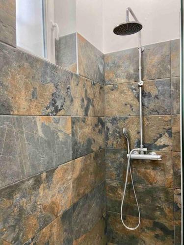 La salle de bains est pourvue d'une douche et d'un mur en pierre. dans l'établissement Un petit cocon en plein cœur du 11eme, à Paris