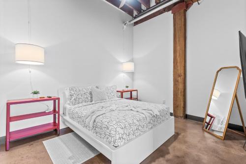 a white bedroom with a bed and a mirror at Stylish Riverfront Loft- Gym - Walk to Arch, Casino, Conventions in Saint Louis