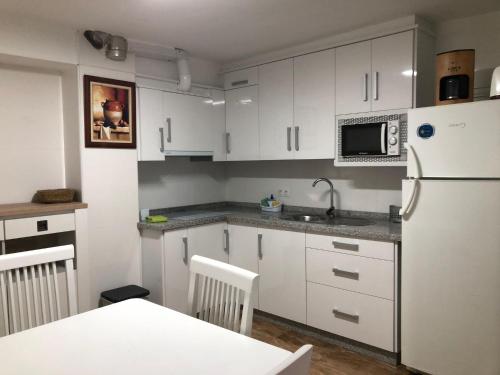 a kitchen with white cabinets and a white refrigerator at La Gloria in Guadix