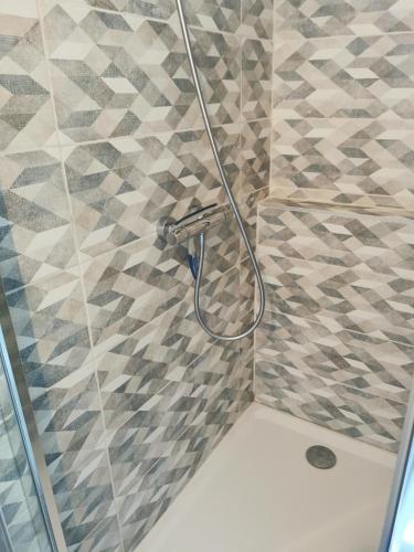 une douche avec un tuyau sur un mur carrelé dans l'établissement Chambre double dans villa avec piscine salle de bains privée, à Roézé-sur-Sarthe