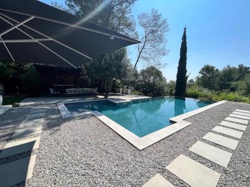einen Pool mit Sonnenschirm im Hof in der Unterkunft Propriété avec vue panoramique in Montferrier-sur-Lez