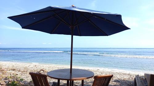 a table with an umbrella on the beach at Dessert Point Bungalow in Sekotong