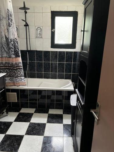 - une salle de bains en noir et blanc avec une baignoire et une fenêtre dans l'établissement Le Nid du Bois Rond, à La Villeneuve