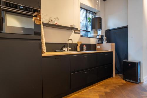 a kitchen with black cabinets and a sink at Noard 41 in Workum