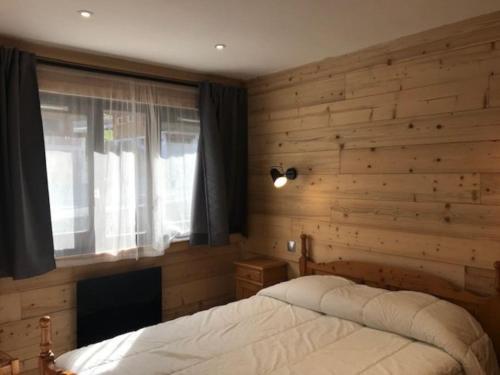 - une chambre avec un lit et un mur en bois dans l'établissement Isabela 63 - Multipass inclu, à Châtel