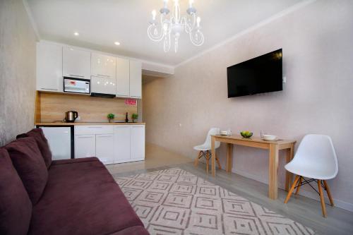 a living room with a couch and a table and a kitchen at Almaty Cozy Apart Hotel in Almaty