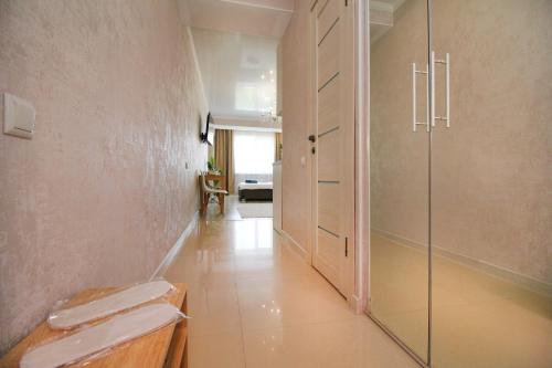 a bathroom with a glass shower stall and a hallway at Almaty Cozy Apart Hotel in Almaty