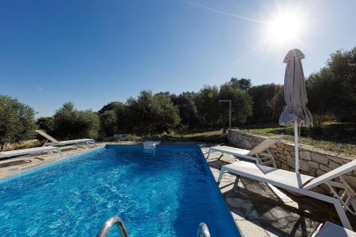 una piscina con sombrilla y 2 sillas y una piscina en Komfort-Villa mit privatem Pool, en Agia Triada