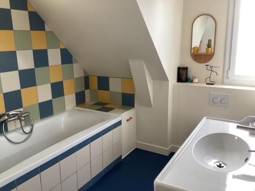 une salle de bain avec un lavabo et une baignoire dans l'établissement Jolie Maison proche plage Sables Blancs, à Concarneau