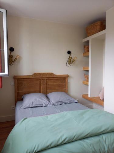 un lit avec une tête de lit en bois dans une chambre dans l'établissement Gite du vieux Puits, à Merlimont