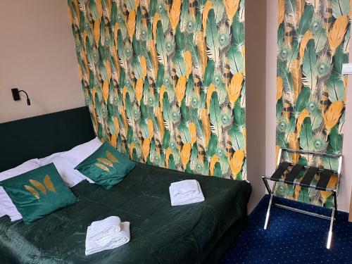 a bedroom with a green bed with towels on it at Hotel Bella in Jelenia Góra