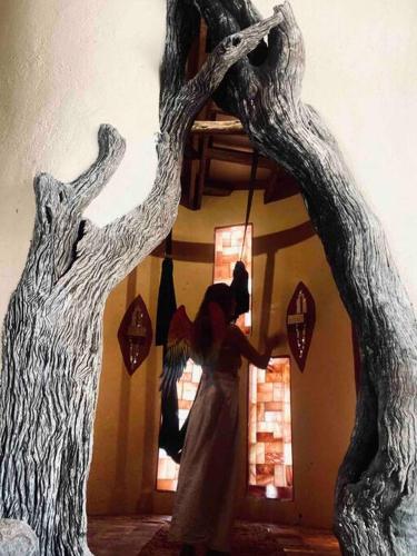 a woman is standing in a room with a tree at The Eco Hut in Hoedspruit