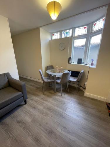 a living room with a table and chairs and windows at 2 Bedroom Apartment on suite bathroom, Southmead Bristol in Bristol