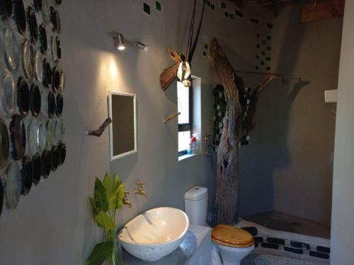 a bathroom with a sink and a toilet and a window at The Eco Hut in Hoedspruit