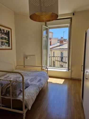 une chambre avec un lit et une grande fenêtre dans l'établissement Le lumineux P2 de ST Guilhem, à Montpellier