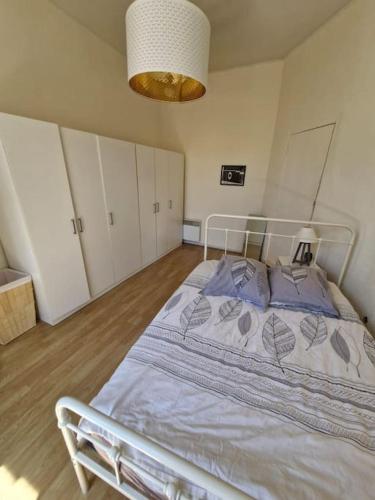 une chambre avec un lit blanc avec des oreillers bleus dans l'établissement Le lumineux P2 de ST Guilhem, à Montpellier