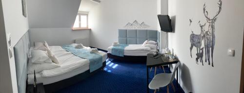 two twin beds in a room with blue carpet at Hotel Bella in Jelenia Góra