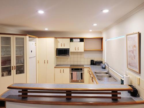 a kitchen with white cabinets and a wooden table at Sea view 5 bedroom holiday house in Whangaparaoa