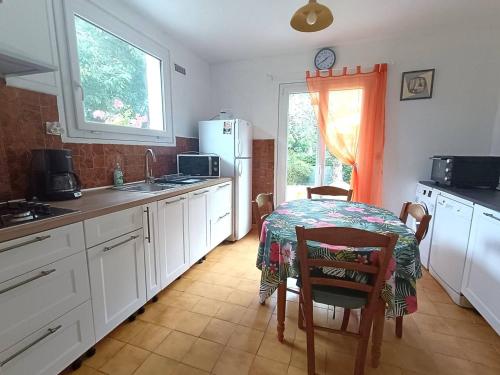 une cuisine avec une table et des placards blancs dans l'établissement Maison avec WIFI, jardin clos, terrasse, à 600m de la plage - Pleumeur-Bodou - FR-1-368-425, à Pleumeur-Bodou